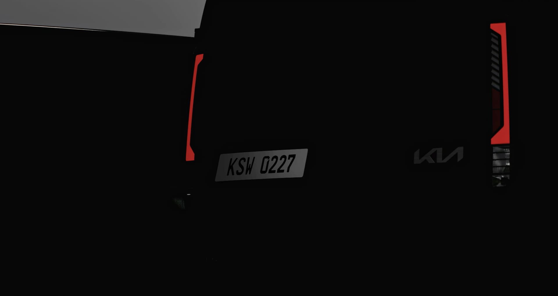 Rear view of the Kia PV5 Cargo in low light, emphasizing the tail lamps 